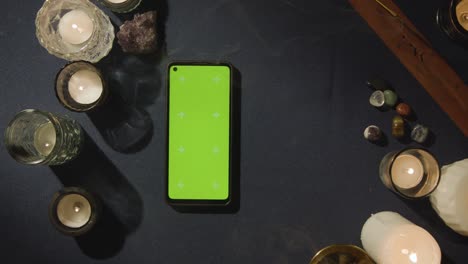 overhead shot of person giving tarot card reading with green screen mobile phone on table