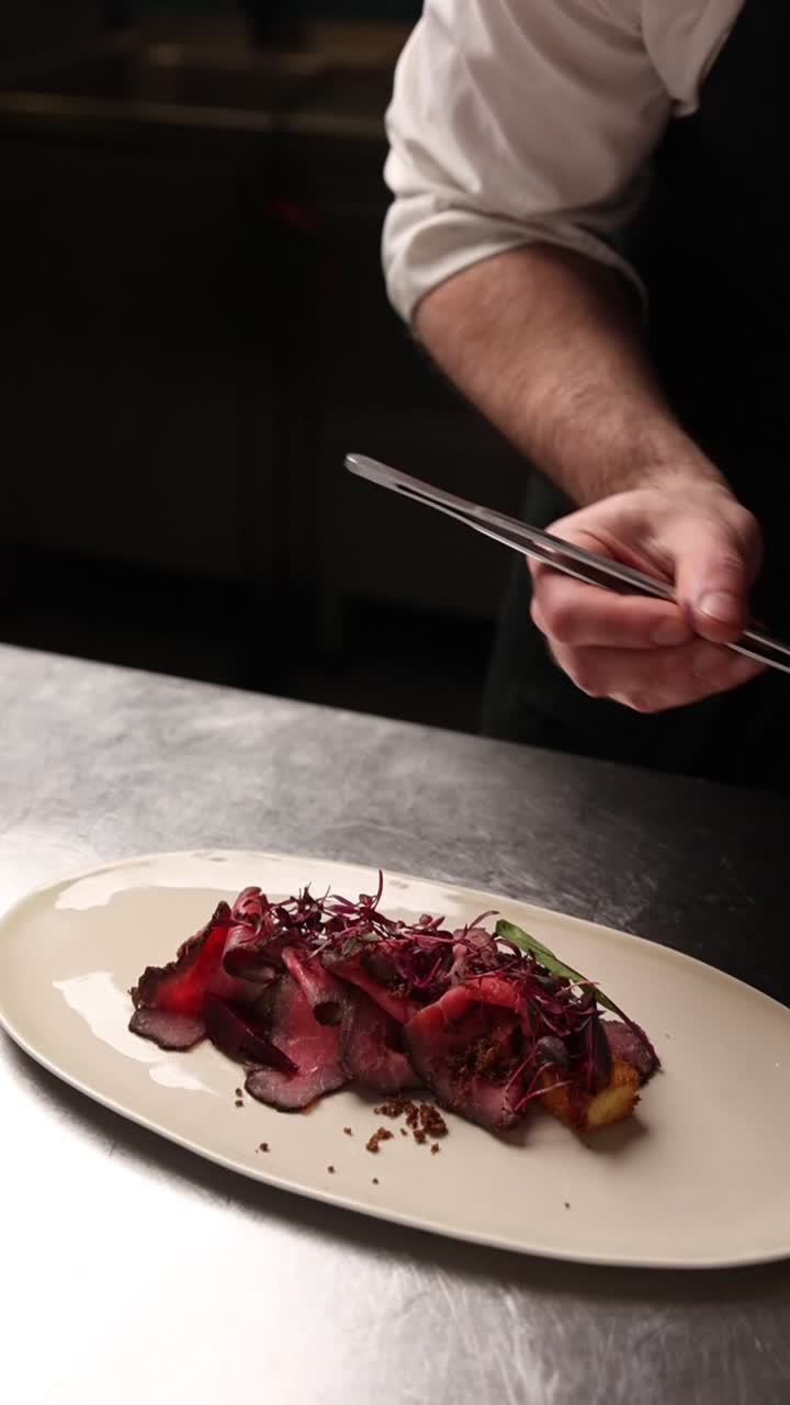 Chef Plating Gourmet Meat Dish with Microgreens in a Professional Kitchen