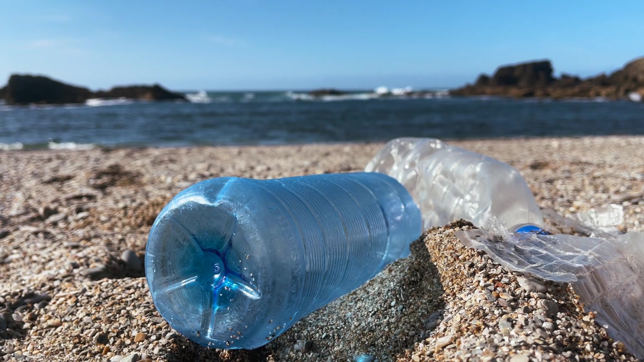 Bottiglia di plastica portata a riva su una spiaggia, a simboleggiare l'inquinamento e l'impatto del cambiamento climatico