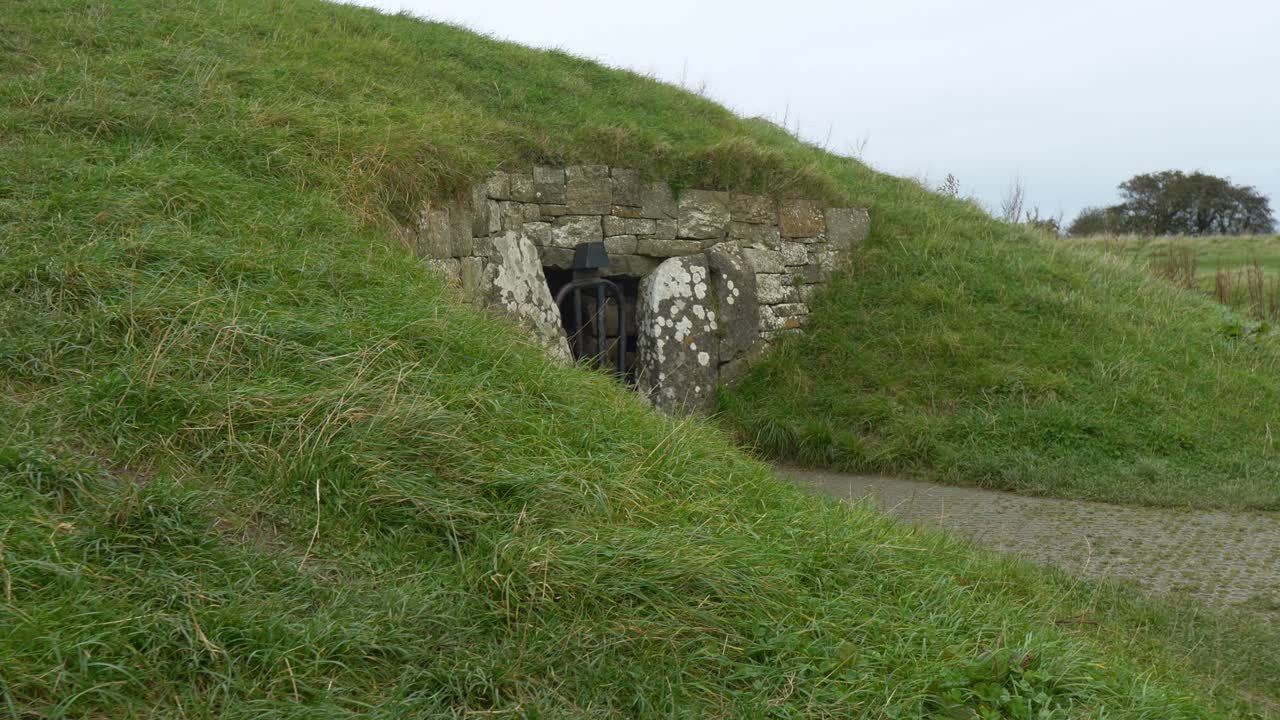 Gammel gravkammerindgang på grøn bakke i Irland vækker historie og mystik.