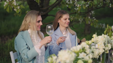 hen party in garden in spring day happy women are clinking glasses with wine and cocktails