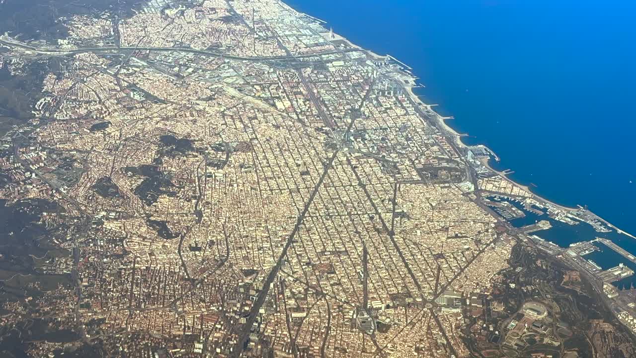Prospettiva aerea elevata dalla cabina di pilotaggio di un jet della città costiera di Barcellona mentre sorvola la città illuminata dalla calda luce del tramonto. Vista da 5000m di altezza