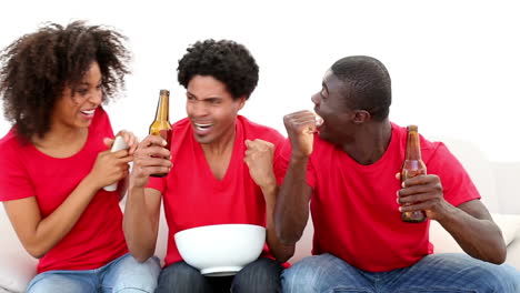 football fans in red sitting on couch cheering