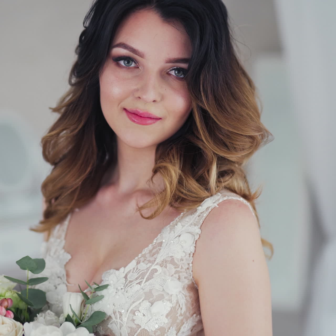 Wedding bouquet of creamy roses in the hands of a beautiful bride. Lovely young woman dressed in white wedding dress is holding flowers. Close-up.