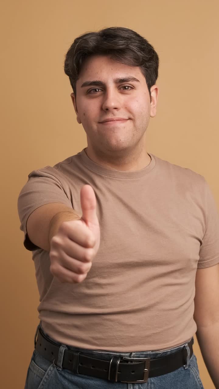 Young man gesturing agreement with thumb up