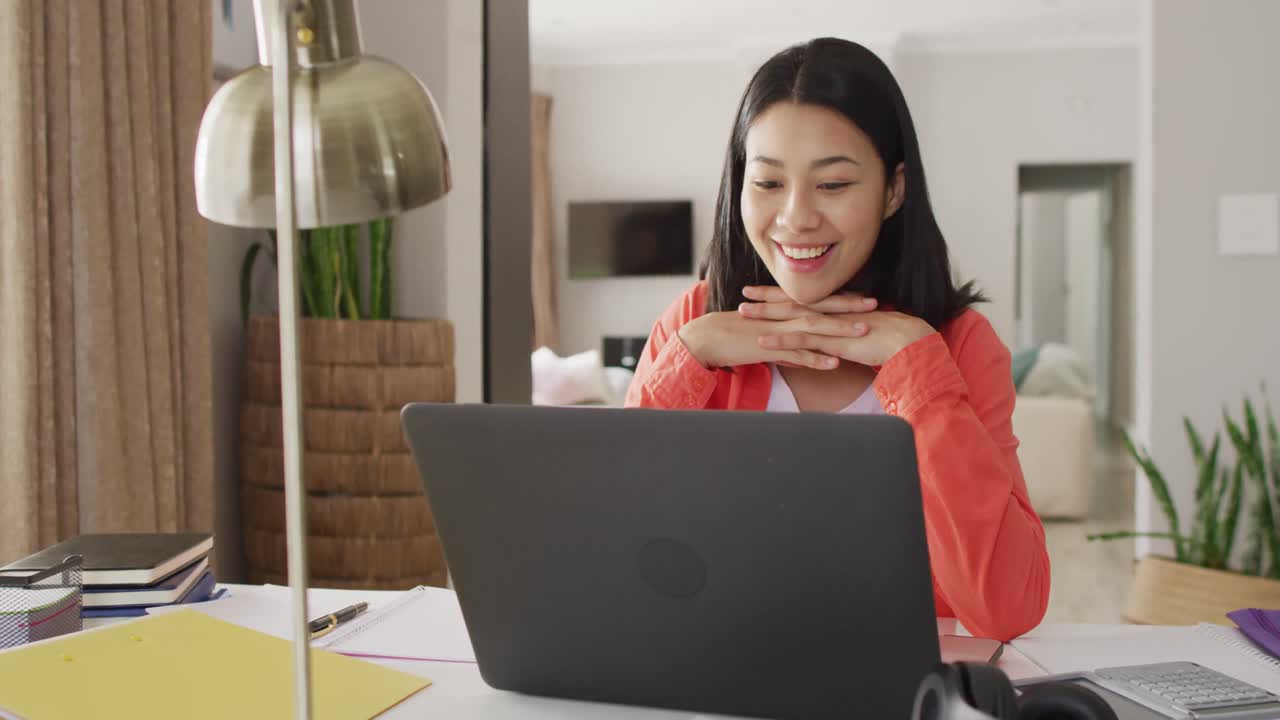 노트북을 사용하는 어두운 머리카락을 가진 미소 짓는 두 인종의 여성의 비디오