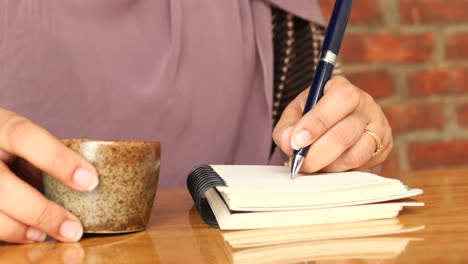 mujer tomando notas en un café