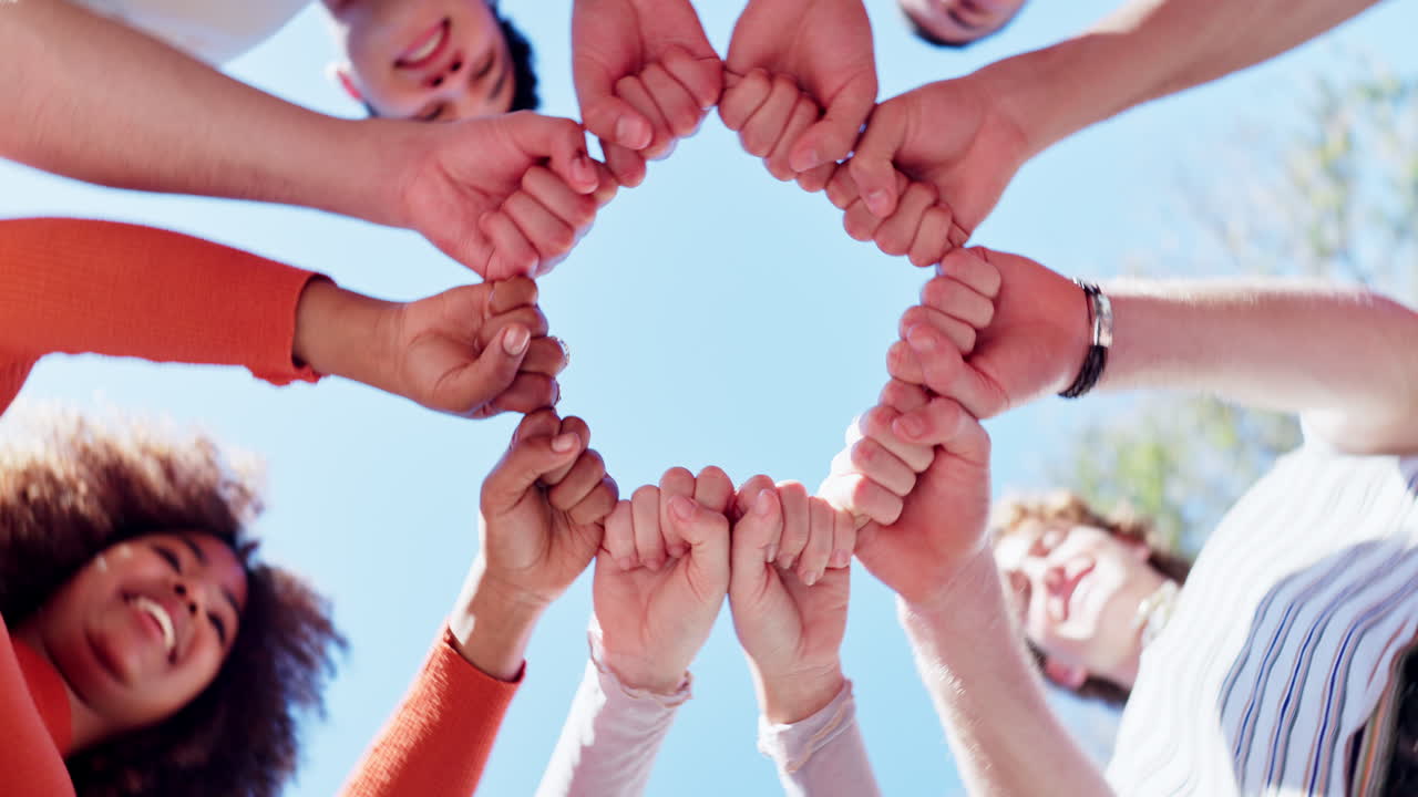 Diverse group of young people joining hands in a circle