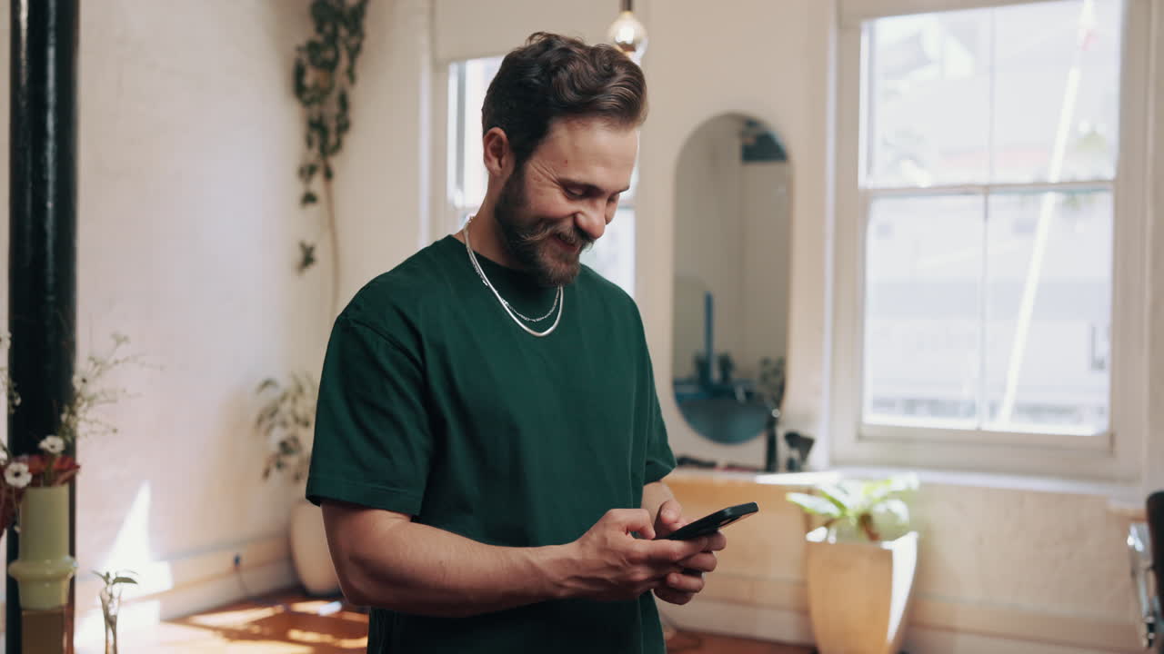 Giovane uomo felice che sorride mentre scrive messaggi sullo smartphone