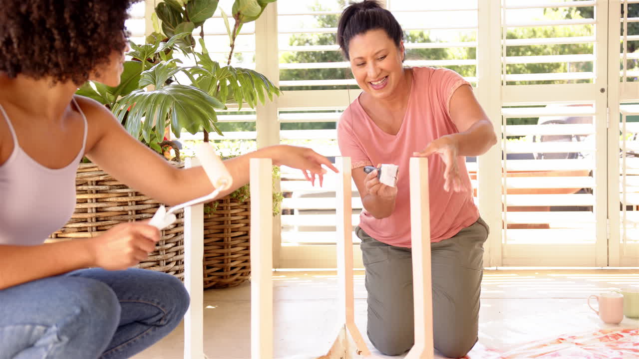 Painting furniture together, mother and adult daughter enjoying DIY home improvement project indoors