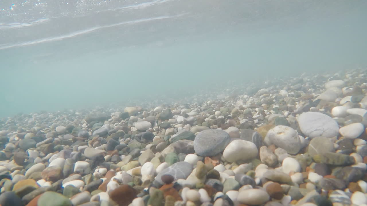 다양한 크기의 바다 돌이 서로 다른 방향의 수중 촬영에서 서핑과 함께 흔들립니다.