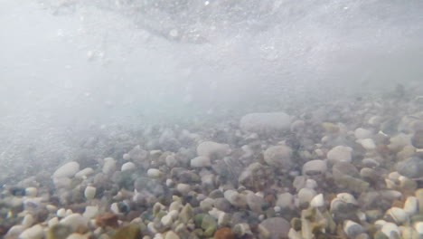 sea stones of different sizes sway with the surf in different directions underwater shooting