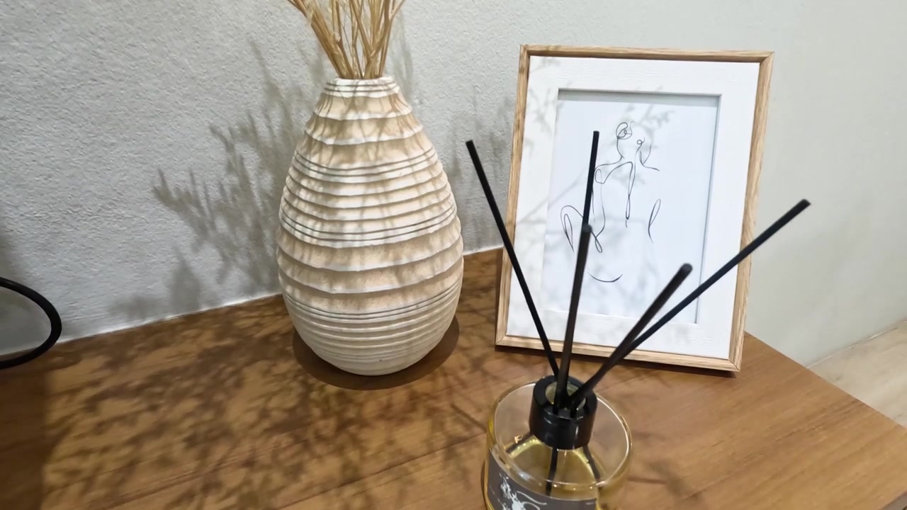 Um zoom lento revela um vaso de cerâmica, moldura de arte linear e difusor de varetas.