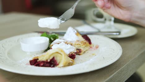 unrecognizable man in white t-shirt taking desert strudel at the restaurant using fork and knife with pieces of ice cream