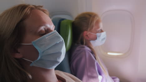 a woman with a child fly on an airplane, they are wearing protective masks. tired of the tegel flight