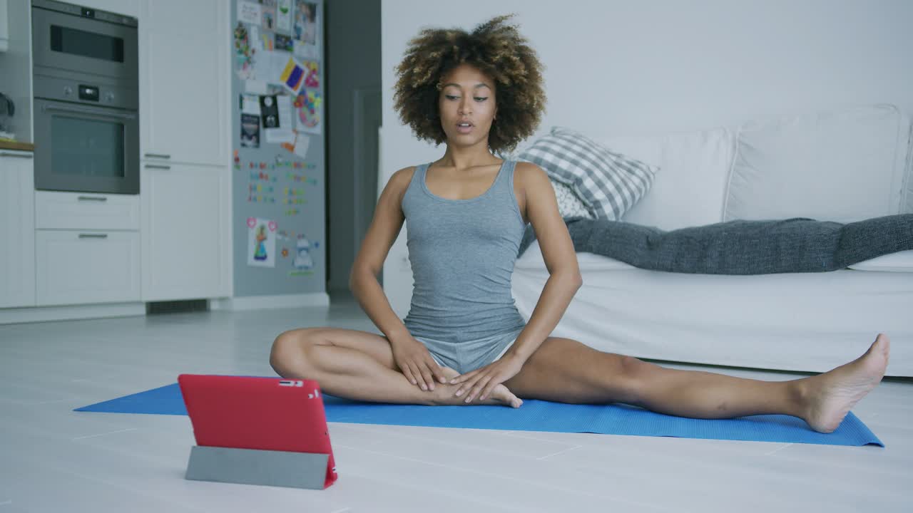 mujer joven entrenando en casa con tableta