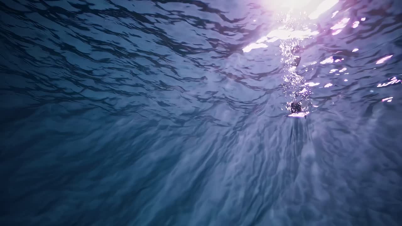 Underwater video capturing sunlight filtering through waves. Shot from below at an upward angle