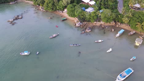 drone aerial pan down and rise over tropical blue water in thailand with speedboats in the water