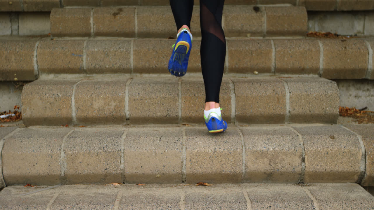 sección baja de una atleta femenina haciendo ejercicio en las escaleras de un recinto deportivo 4k