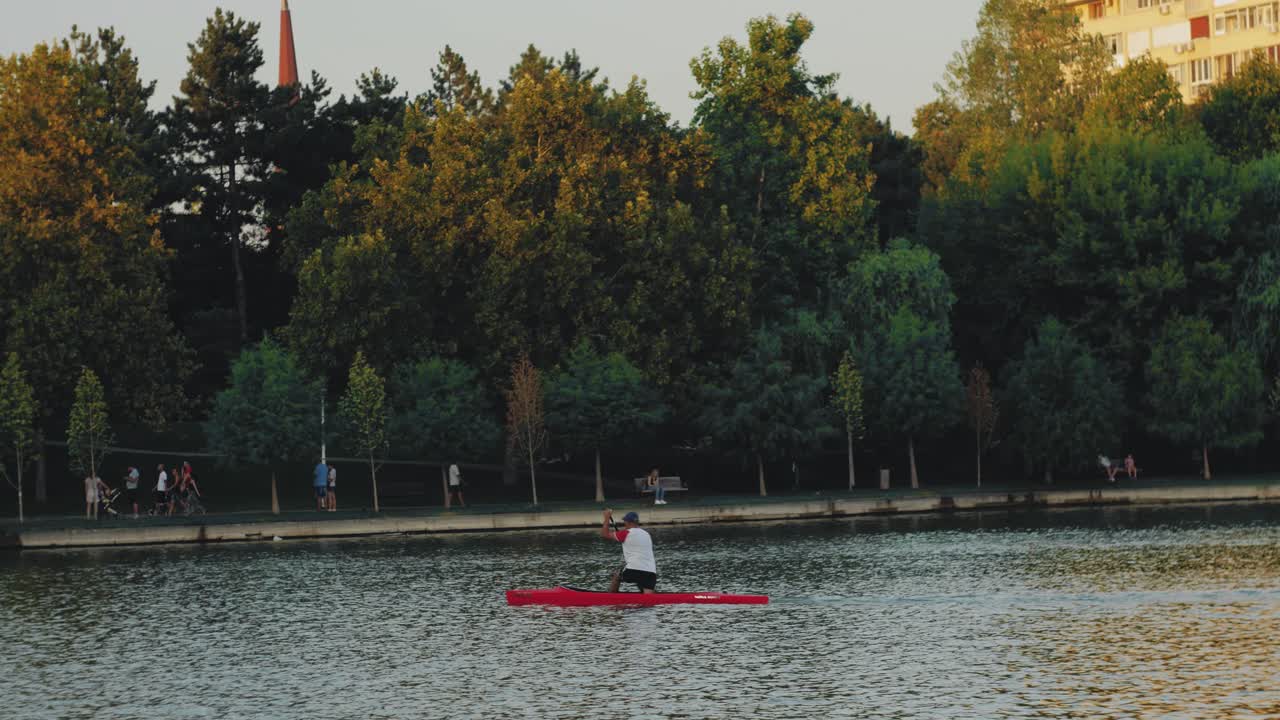 toma estática que muestra a un hombre desde atrás en el lago, remando en un kayak-1