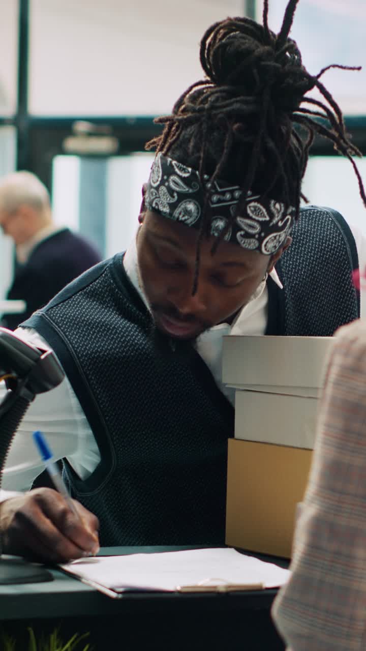 Vertical Video African american deliveryman receiving requested clothes packed in boxes