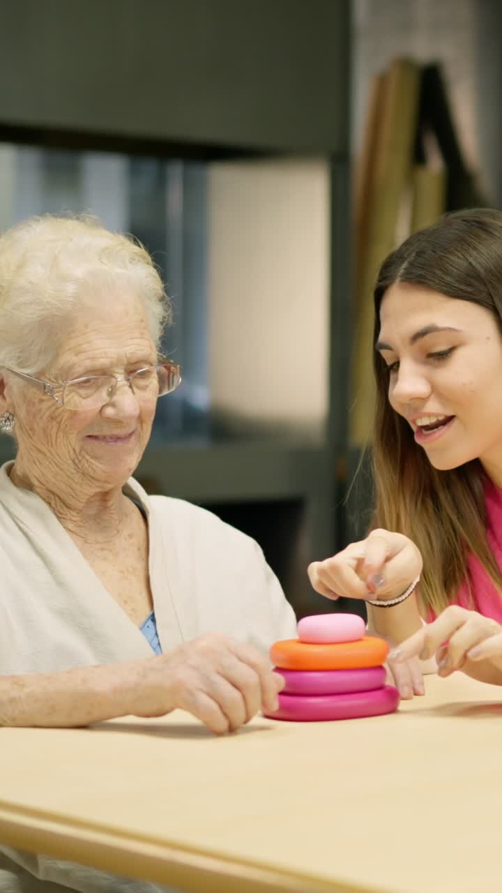 Elderly woman playing stacking rings with young woman