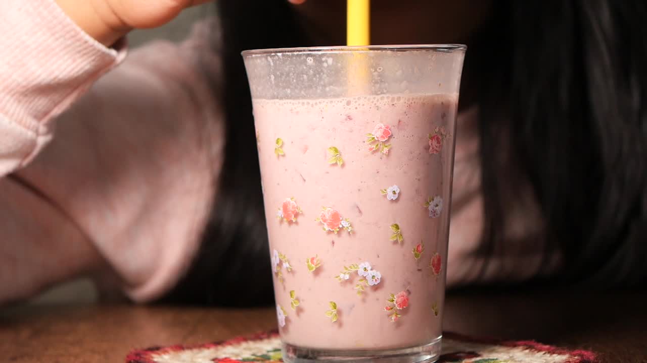 Bambino che beve uno smoothie rosa