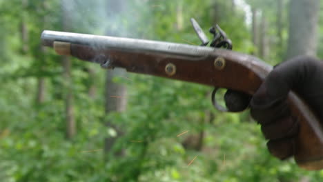 Gloved-hand-squeezes-trigger-to-fire-old-flintlock-pistol,-close-up