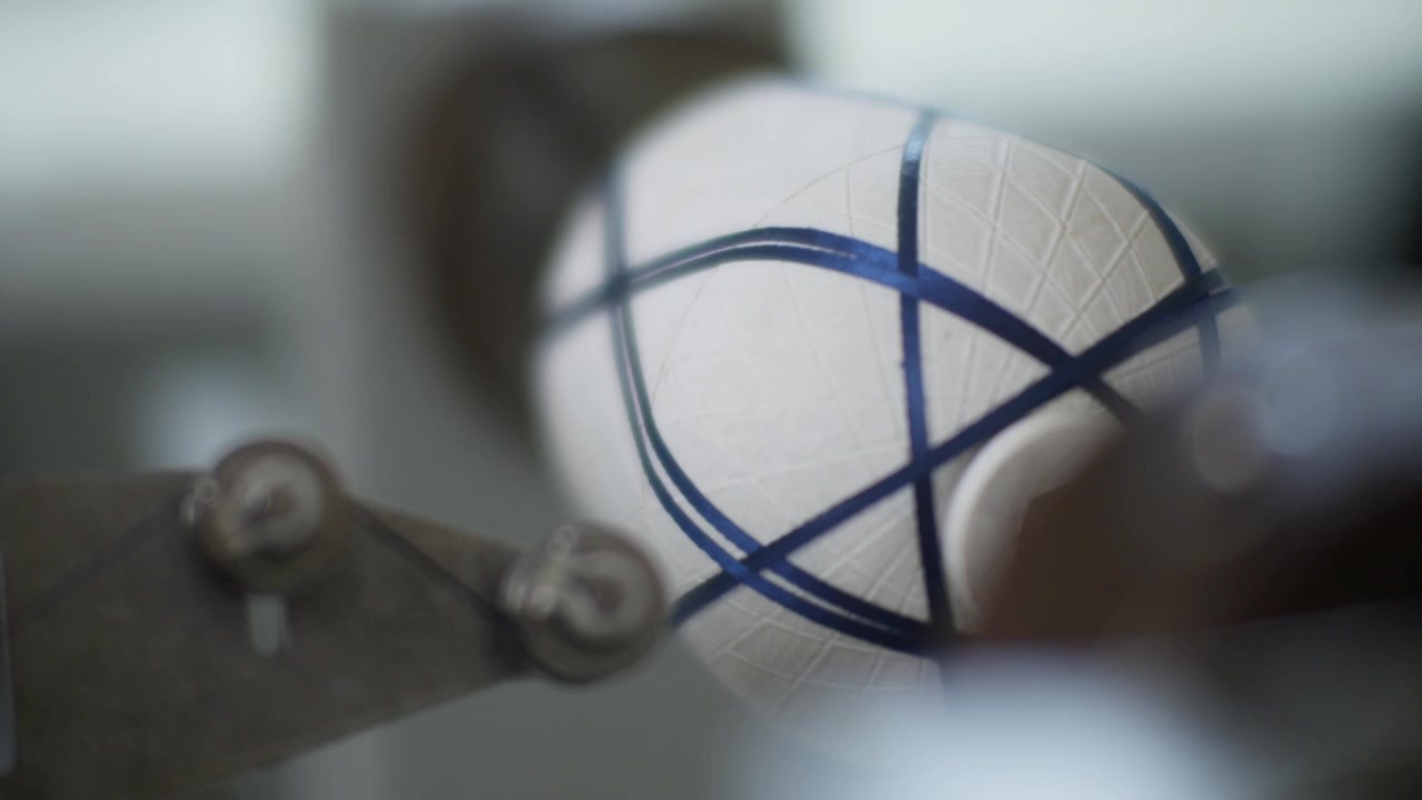 Extreme macro shot focusing on dark carbon fiber strands being precisely wrapped around a textured white mandrel during an industrial filament winding process.