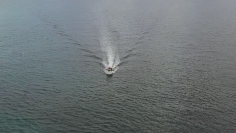 Small-white-boat-cruising-calm-open-ocean-high-angle-circling-aerial