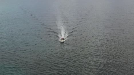 small white boat cruising calm open ocean high angle circling aerial