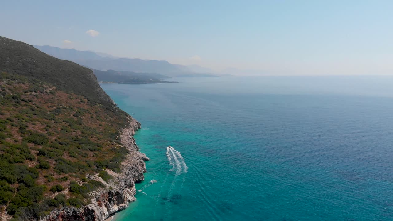Drone following speed boat driving next to cliffs in beautiful ocean