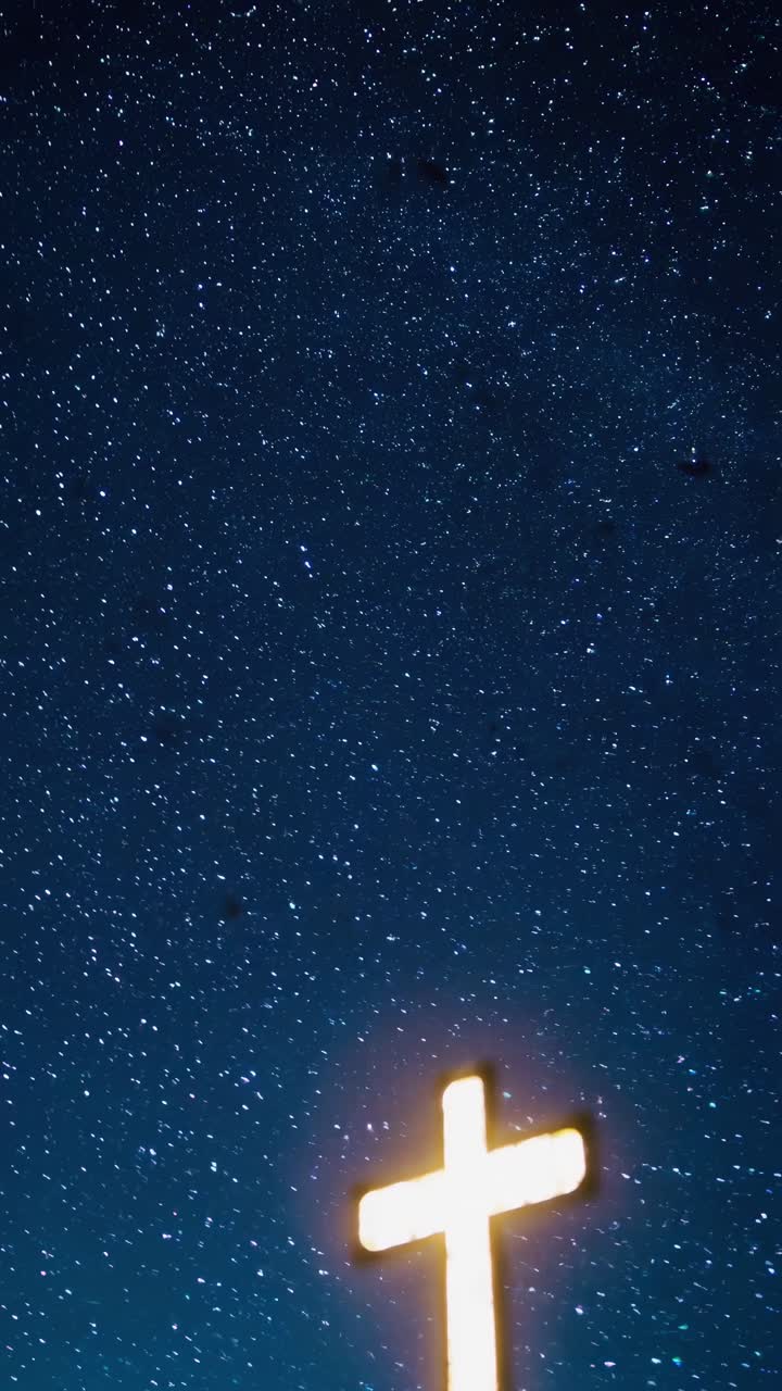 Low-angle video shot of a glowing cross against a starry night sky, capturing a serene and spiritual