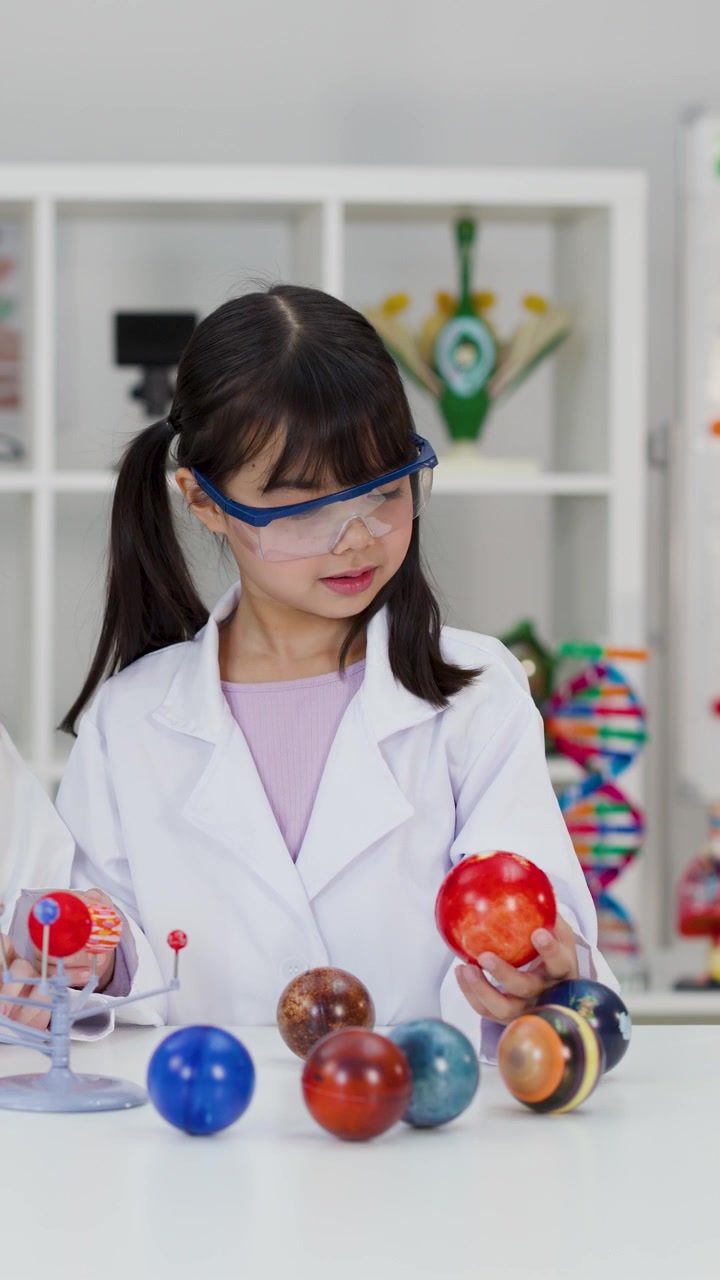 Young Student Wearing Lab Coat and Goggles Studying Solar System Model