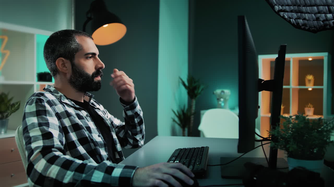 editor, autónomo o diseñador con barba sentado en el escritorio usando el teclado y el mouse de la computadora de escritorio