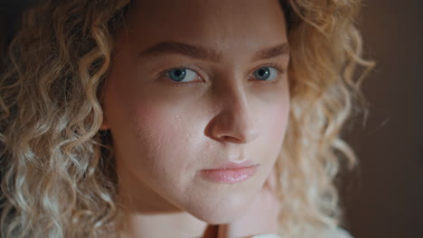 serene woman looking camera in sunlight. portrait curly girl touching