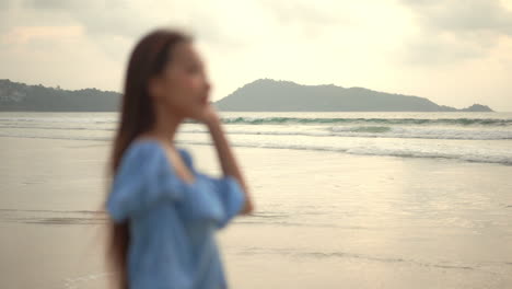 從背景的海灘和波浪轉動到一個漂亮的年輕女人在前景的框架