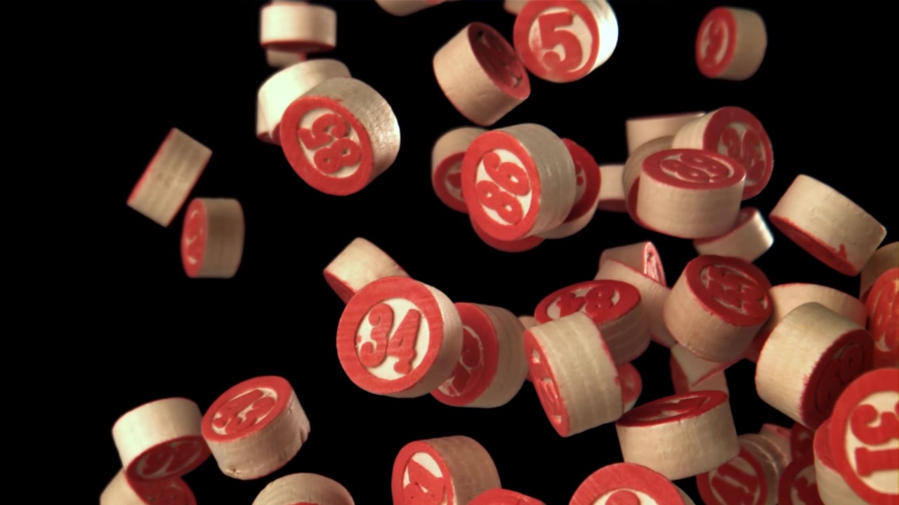 Bolas de bingo rojas numeradas cayendo en cámara lenta sobre fondo negro.
