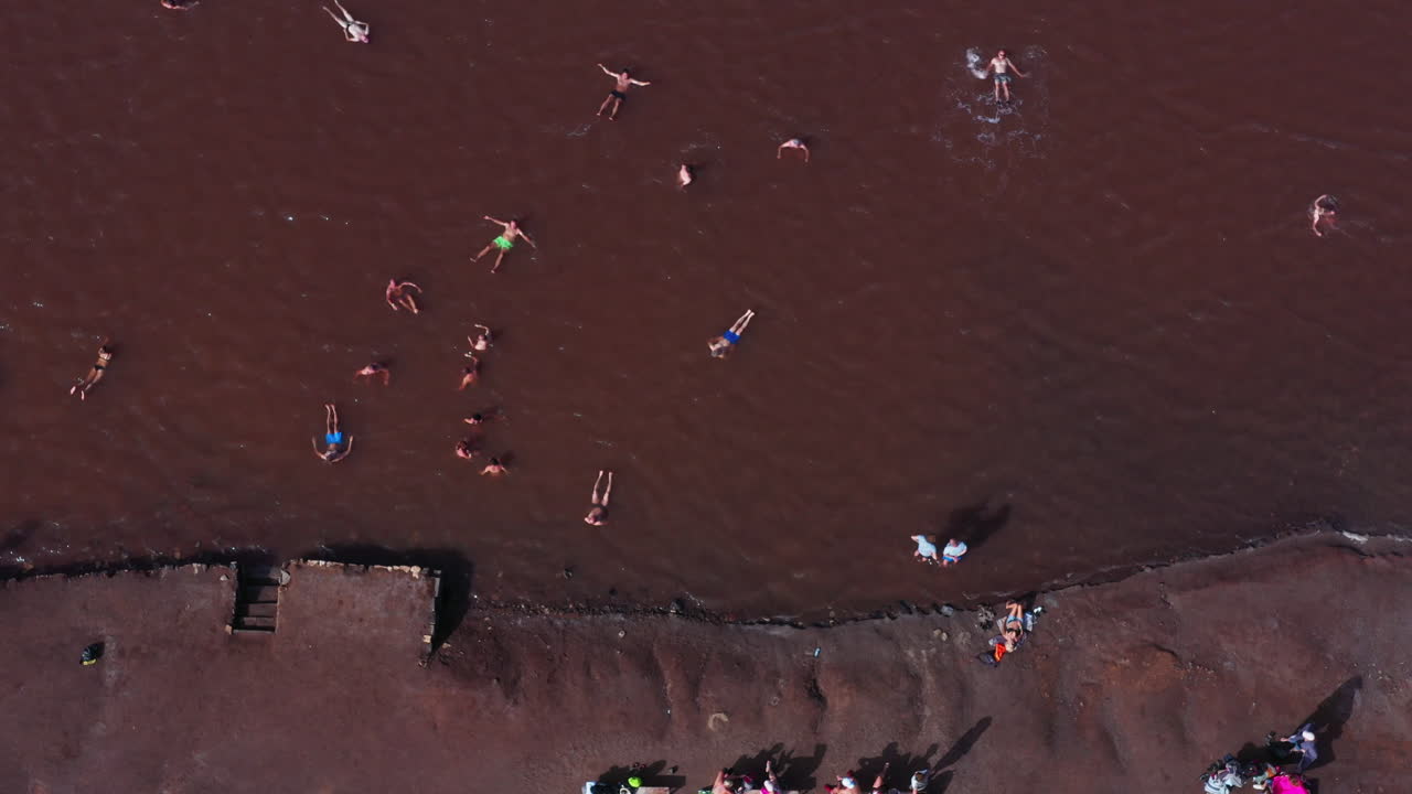 짠 갈색 연못에 수영하는 사람들이 있는 탈라소테라피 소금 호수의 공중 하향식 샷