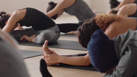 healthy yoga woman practicing head to knee forward bend pose young caucasian female enjoying fitness lifestyle exercising in studio with group of multiracial women