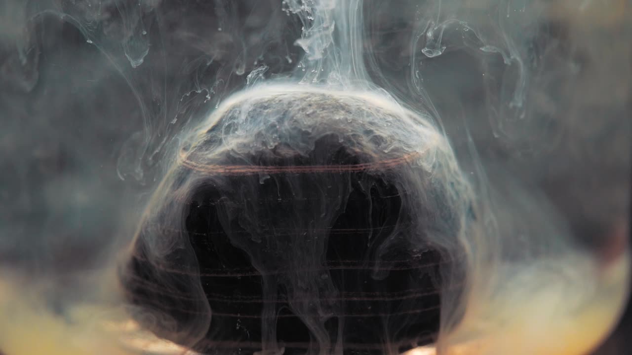 White paint falling on layered rock inside water tank. Slowmotion, stable shot with the Sony a7iii.