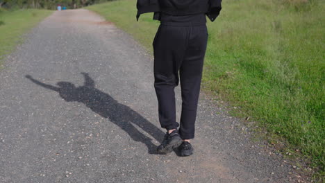 shadow on the dirt road of indian punjabi sikh man walking with open arms on a sunny day