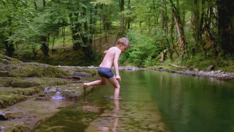 boy playing in a forest stream