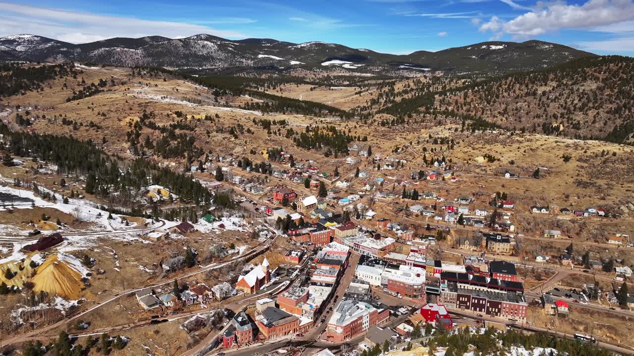 Historic downtown buildings Central City Black Hawk Colorado aerial drone view city townhall winter sunny daytime blue sky Gold mining town tailings neighborhood streets casinos backwards upwards