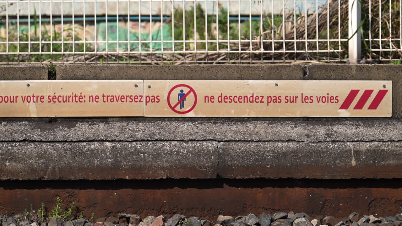Warning sign at a railway platform written in French saying : For your safety: do not cross, do not go down onto the tracks