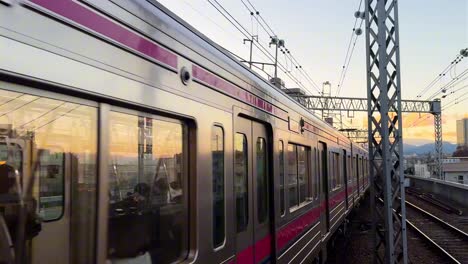 a modern commuter train travels on elevated tracks at sunset with city buildings in the distance