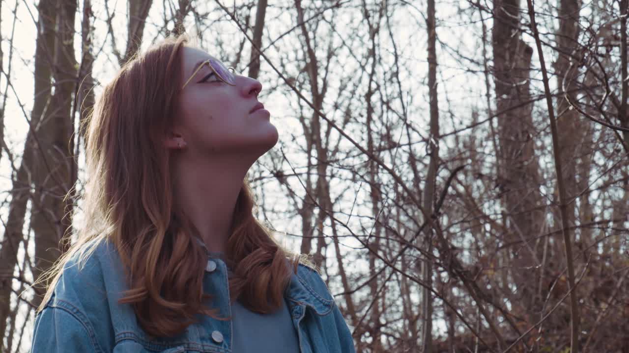 Girl in Forrest looking around with Bird flying away in the Background - Slowmotion