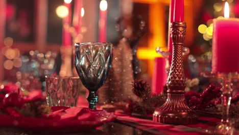 beautiful crockery, candles and beads at table prepared for celebration. red colors for table decoration at christmas dinner.
