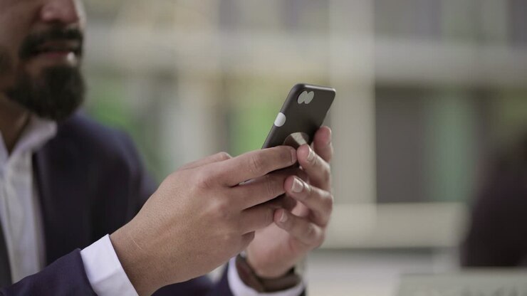 Inquadratura ravvicinata di un uomo d'affari che messaggia con lo smartphone.