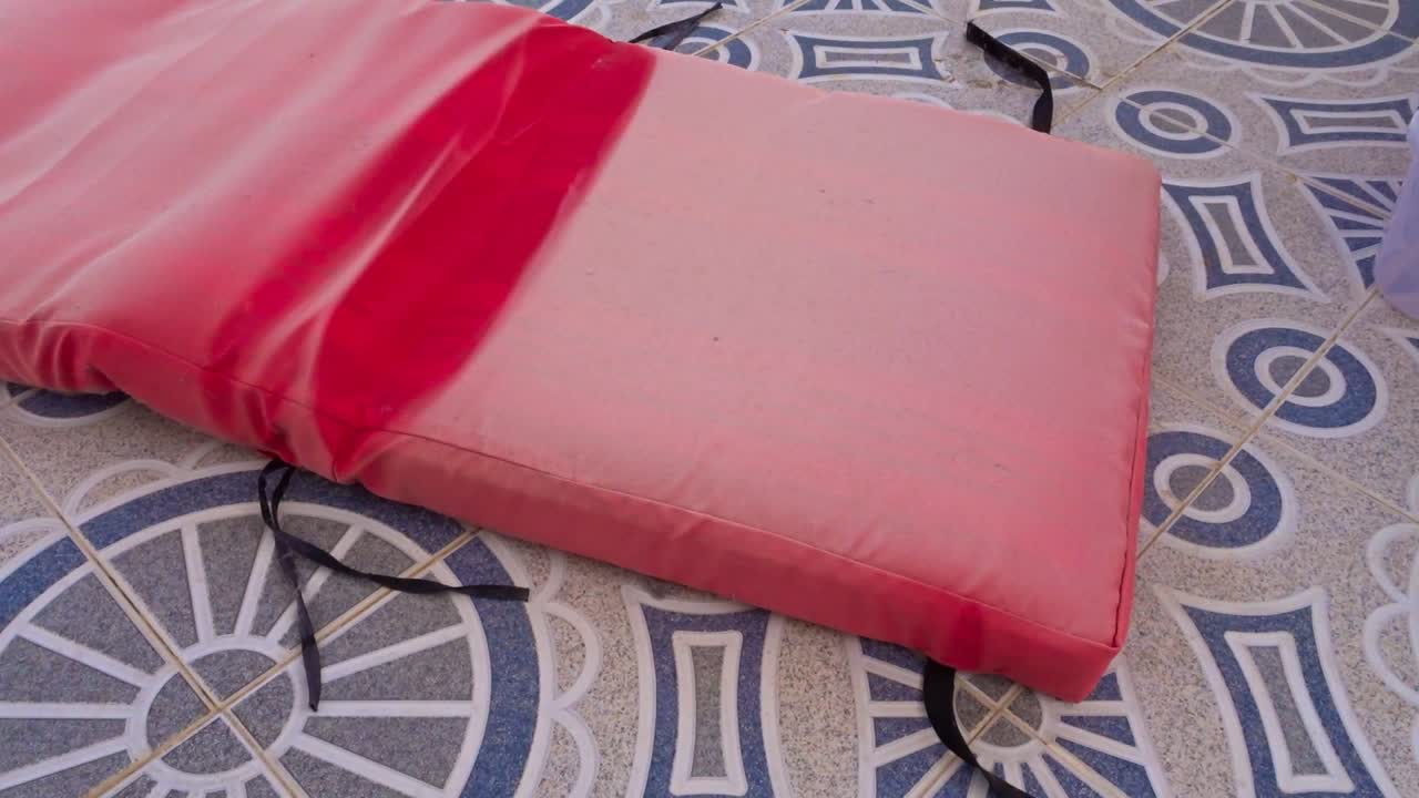 colchón de tumbona usado y descolorido cayendo al suelo